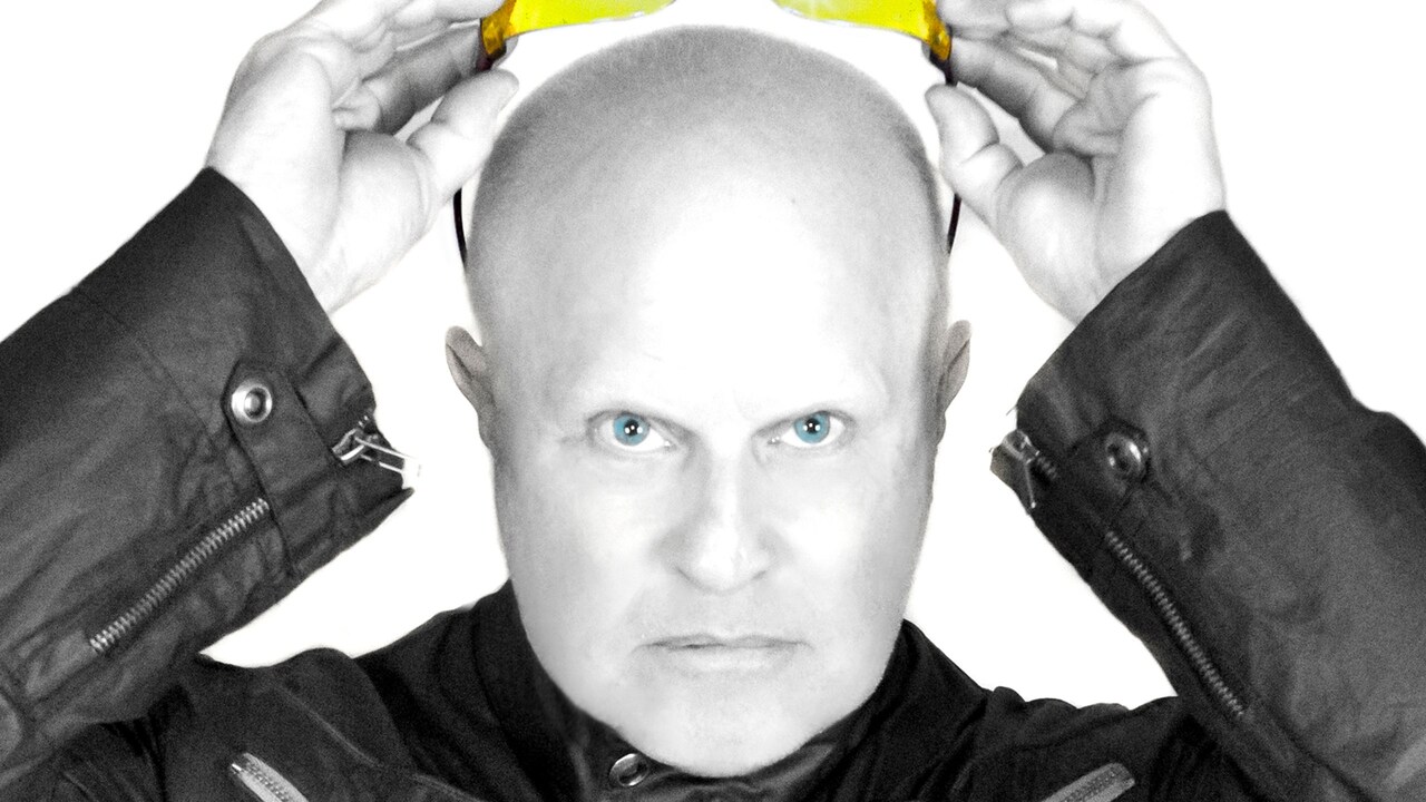 The lead member of A Flock of Seagulls holding sunglasses above his head