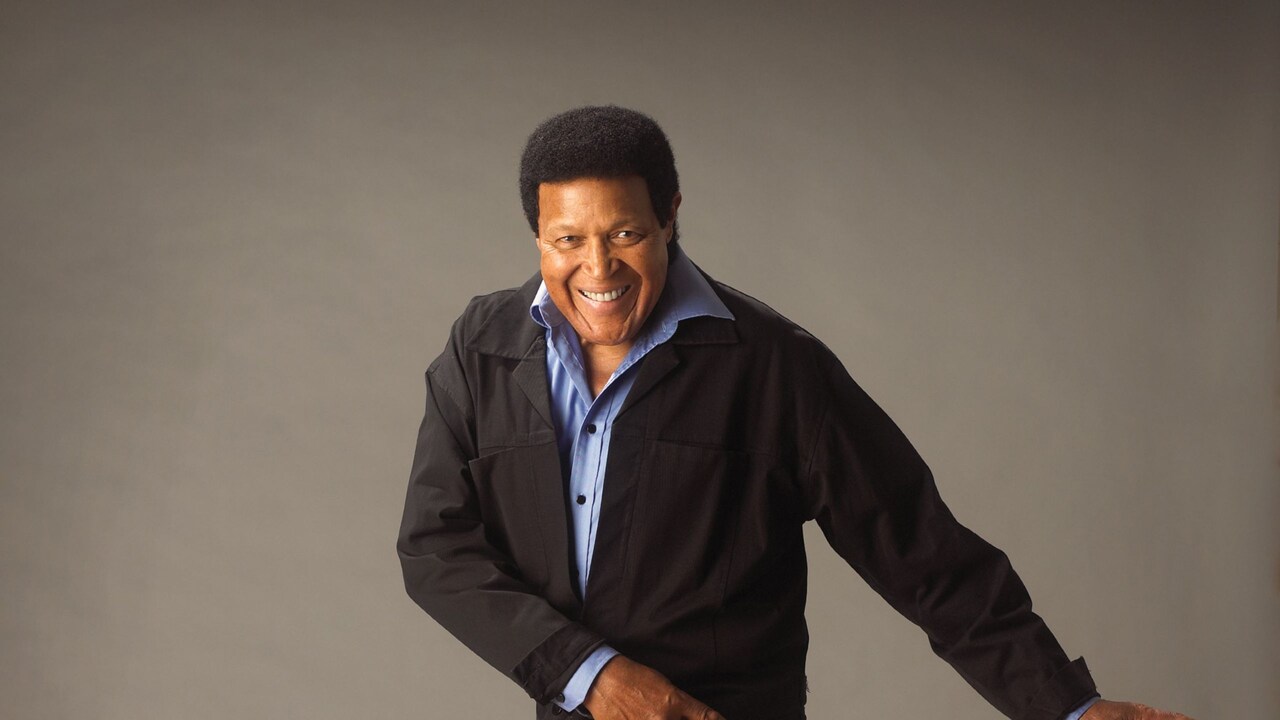 Chubby Checker standing with his leg kicked up and his arms outstretched