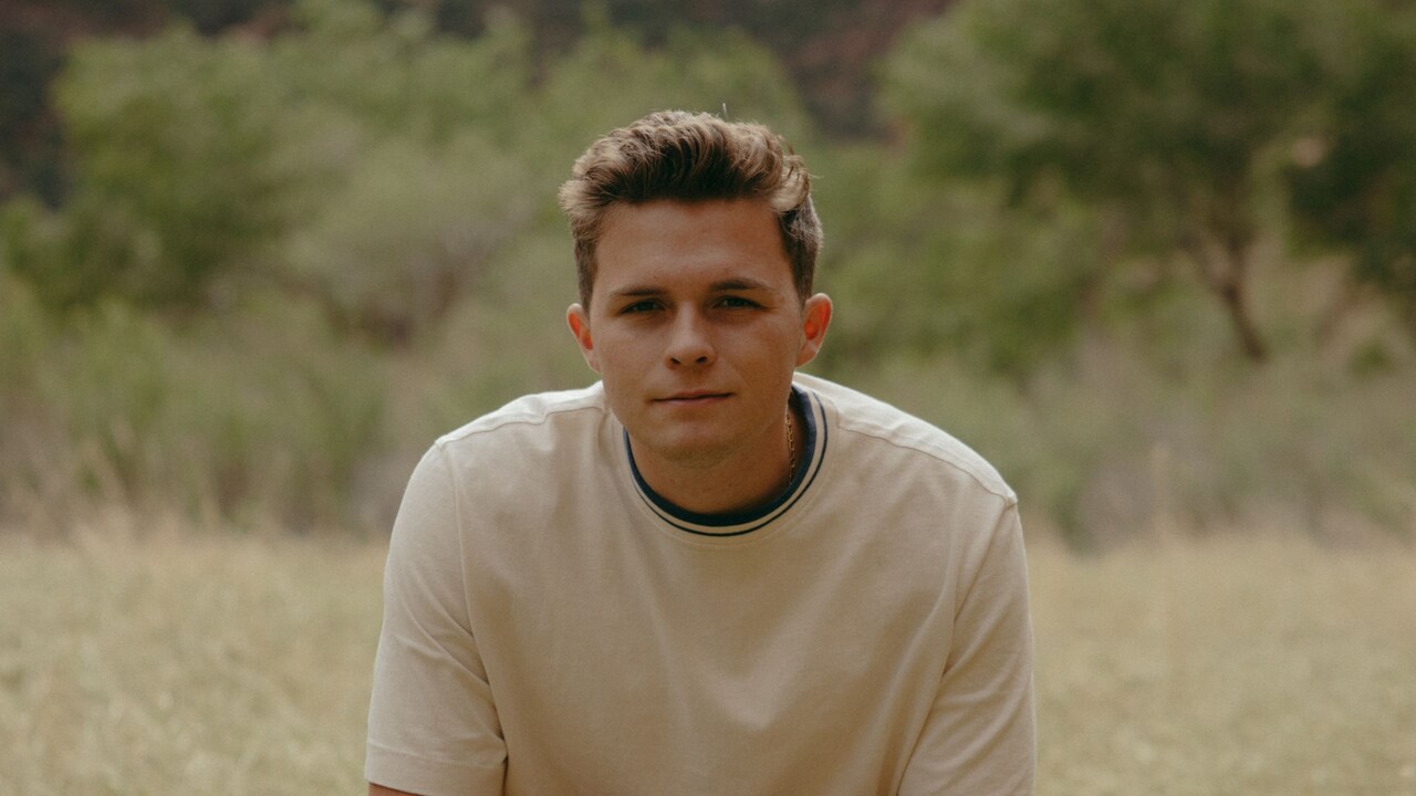Josiah Queen sitting on top of a tree trunk laying on the ground