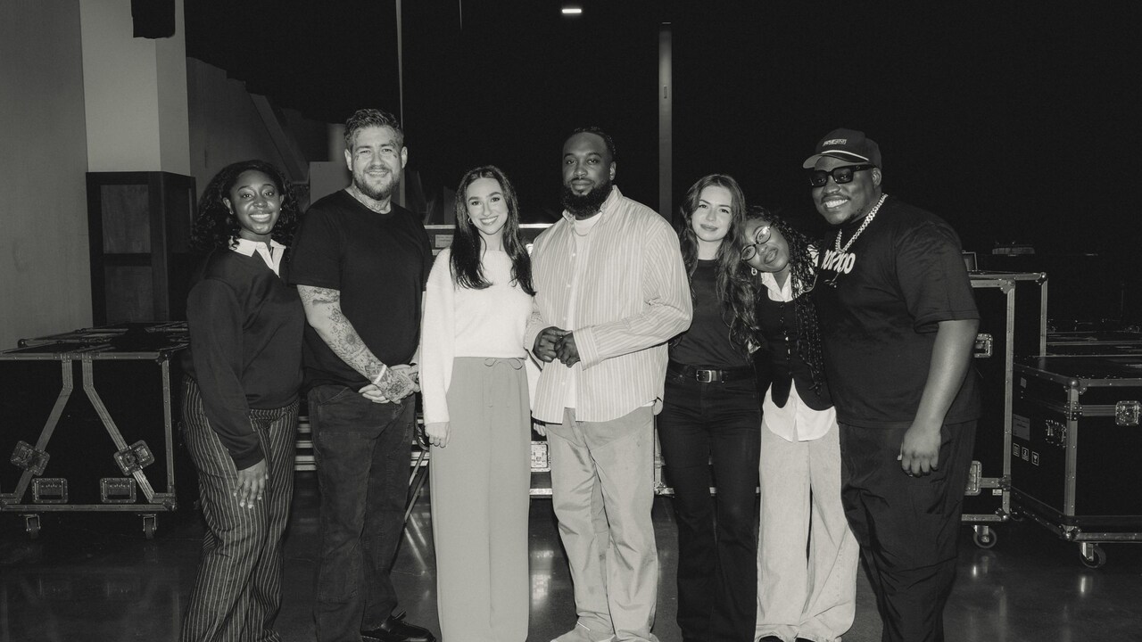 7 members of the group Maverick City Music standing together in front of road cases