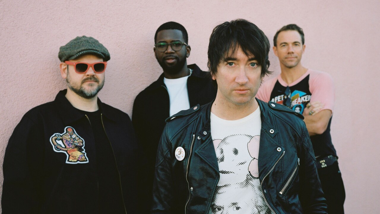 4 members of the group Plain White Ts standing together in front of a wall