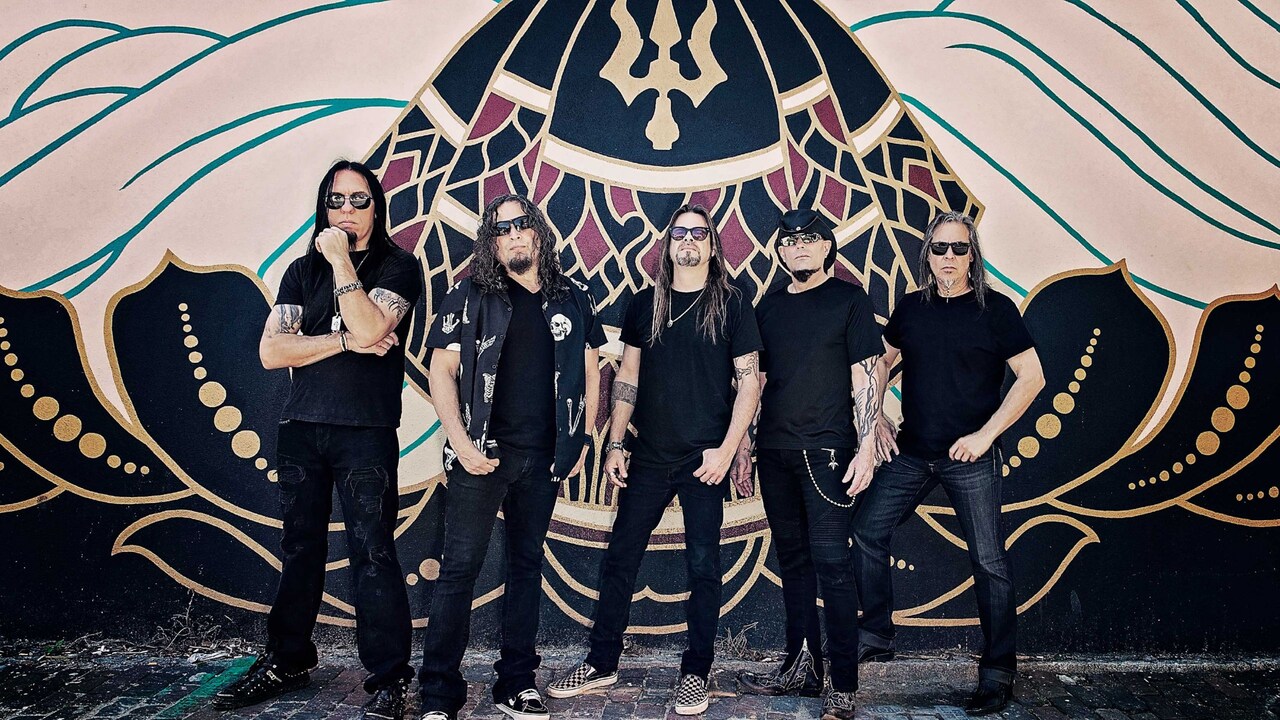 5 members of the group Queensrÿche standing in front of a mural painted on a wall