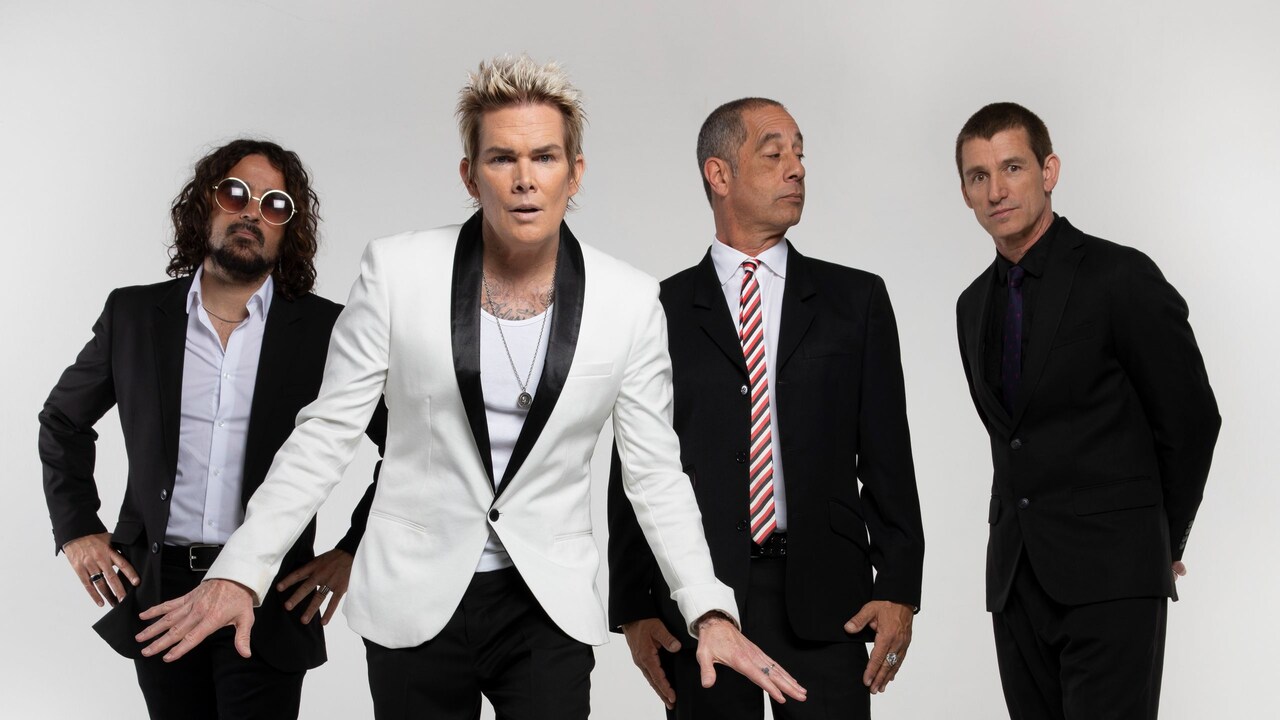 4 members of the group Sugar Ray posing together in front of an empty backdrop