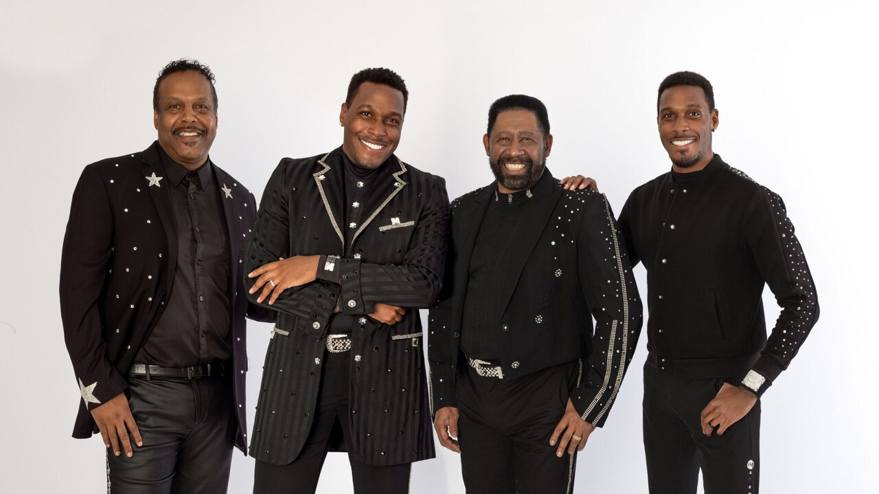 4 members of The Commodores posing together in front of an empty backdrop