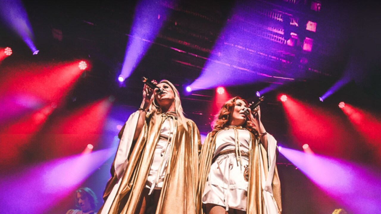 2 members of the group Direct from Sweden singing together on stage as 2 members play instruments behind them