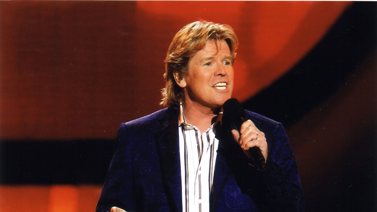 The lead member of Herman’s Hermits standing on stage while singing