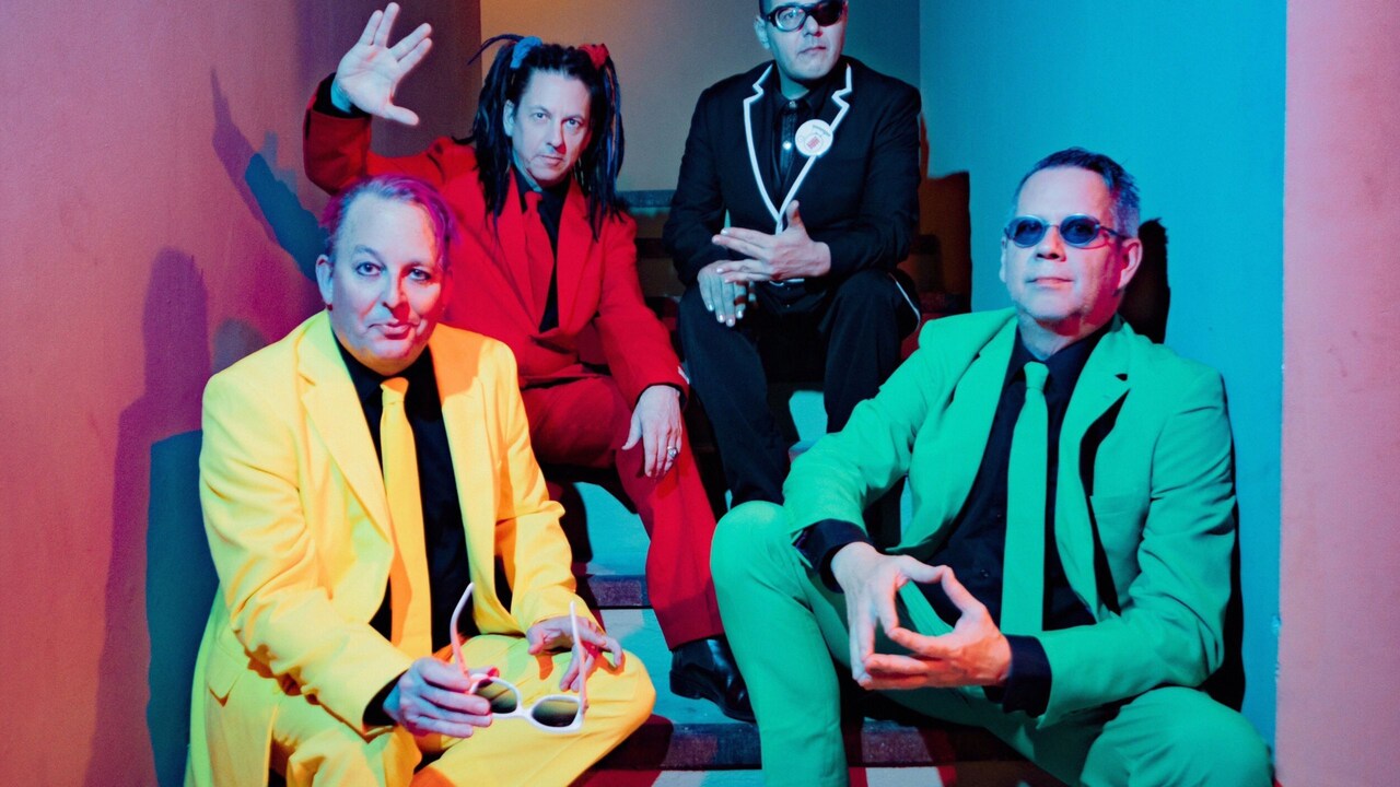 4 members of the group Information Society posing together while sitting on a stairway