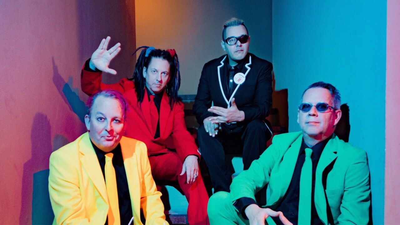 4 members of the group Information Society posing together while sitting on a stairway