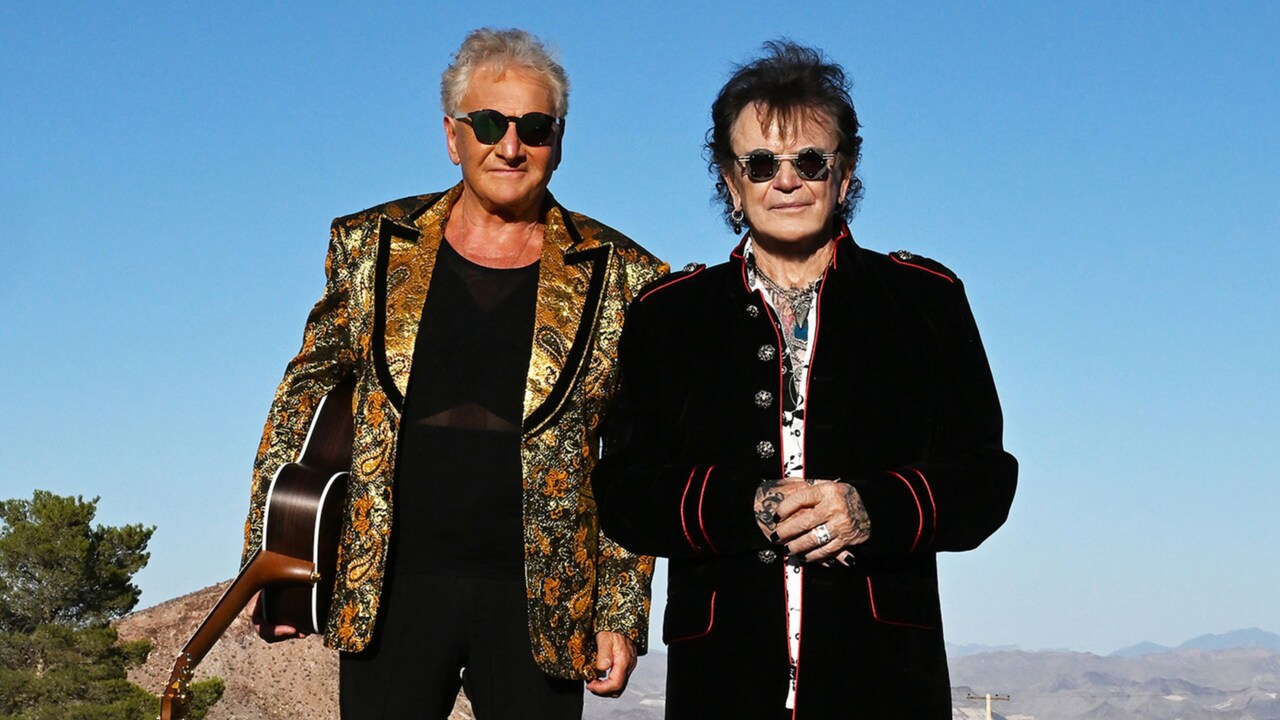 2 members of Air Supply standing in the middle of a road in the desert