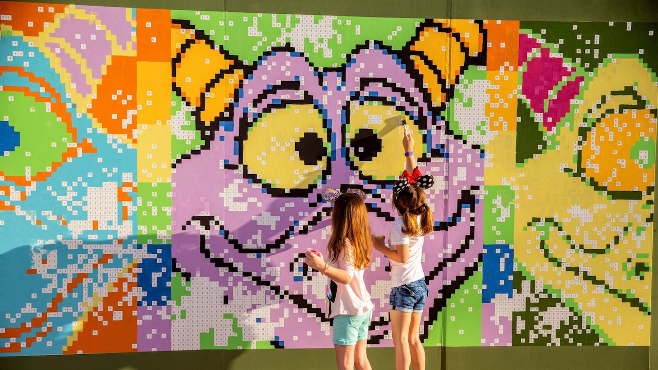 Two girls enjoy a paint by number mural featuring Disney's Figment