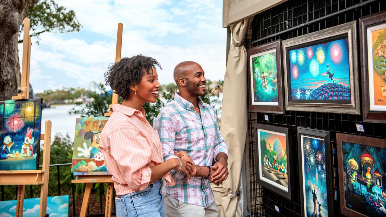 Two adults gazing at artwork on an outdoor display featuring various Disney characters