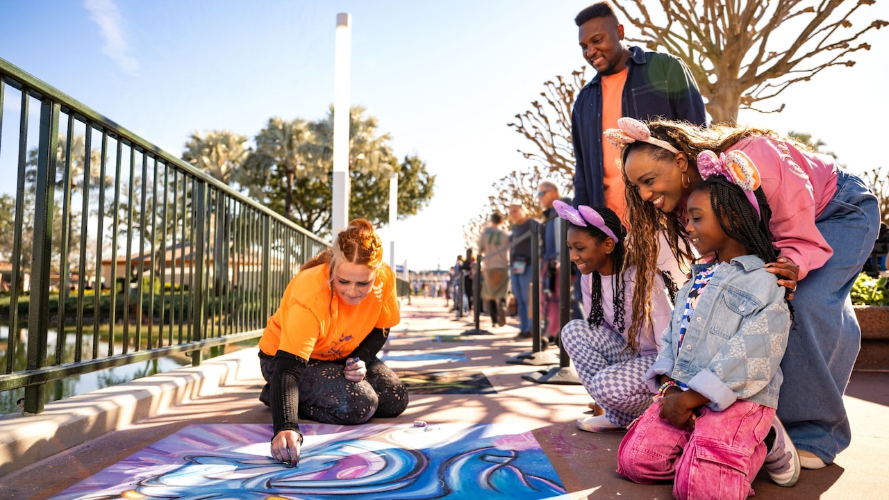 An artist creating a chalk mural on the ground with Guests watching at the Chalk Artist Galleries