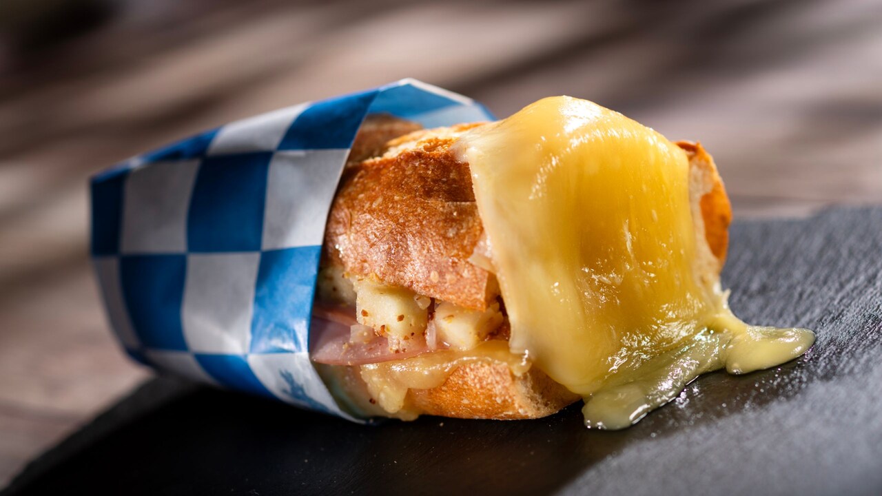 A crusty Warm Raclette Swiss Cheese on a Baguette sandwich filled with jambon and apple mustard relish
