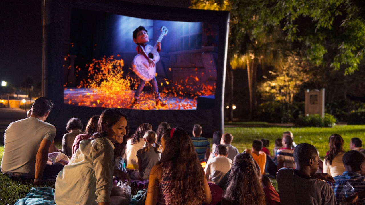 Des visiteurs regardent le film Coco à l’extérieur sur un écran gonflable