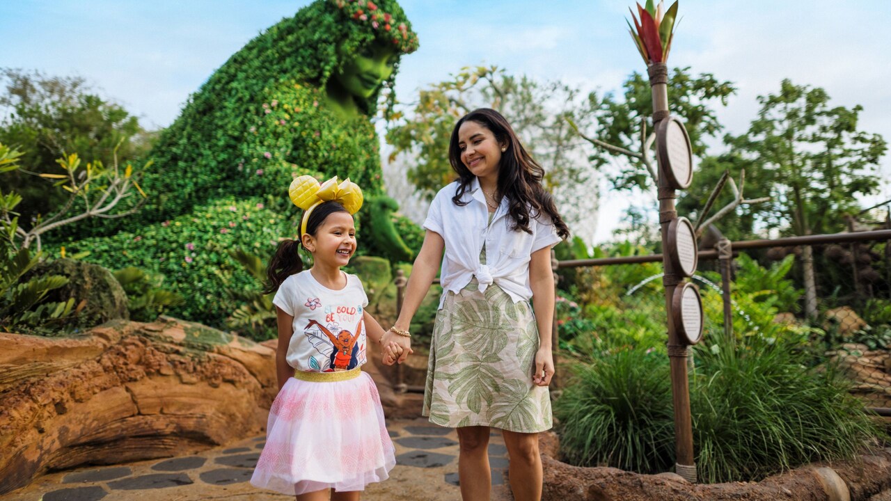 A woman and a girl holding hands in front of a topiary of Te Fiti at Journey of Water, Inspired by Moana in Epcot