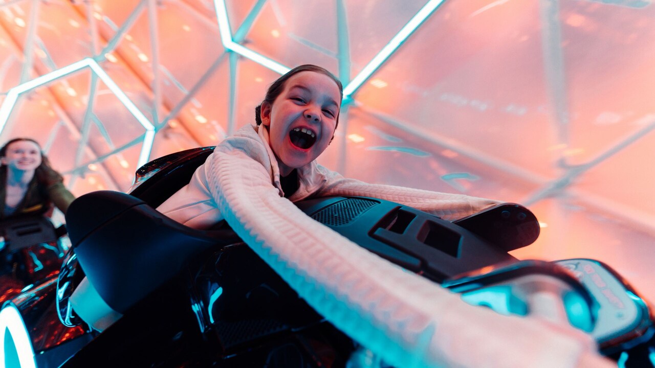 A girl riding Tron Lightcycle Run at Magic Kingdom park