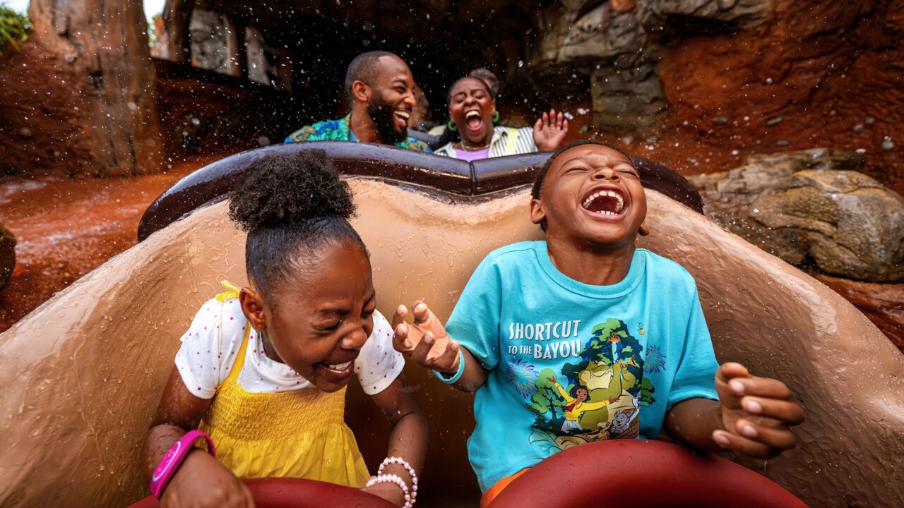Two children laughing while being splashed with water riding on Tiana’s Bayou Adventure at Magic Kingdom park