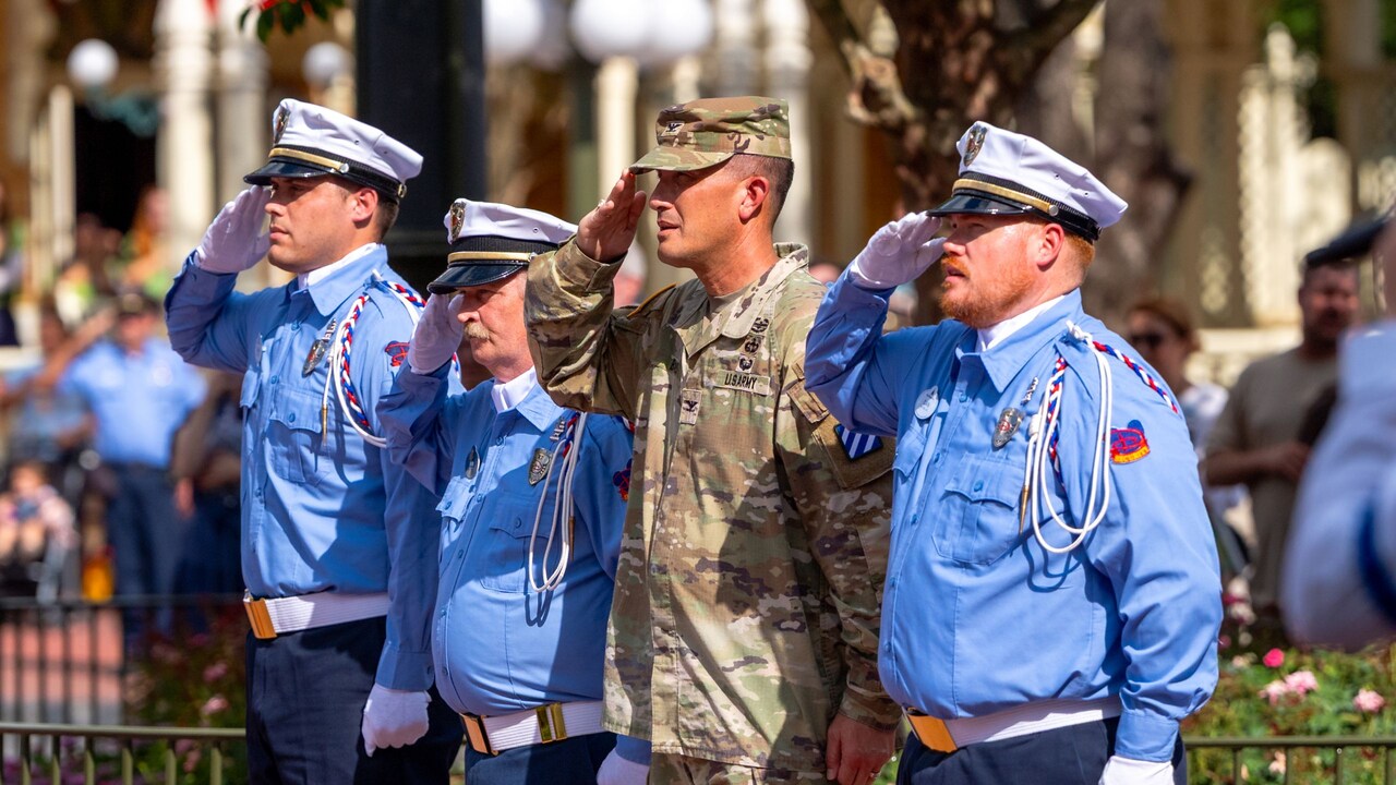 US military service members and Cast Members saluting the flag