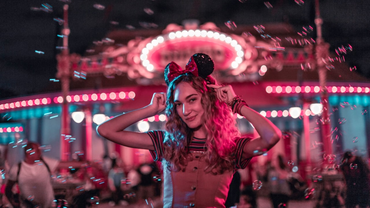 A Guest modeling a Minnie Mouse ear headband near Prince Charming Regal Carrousel