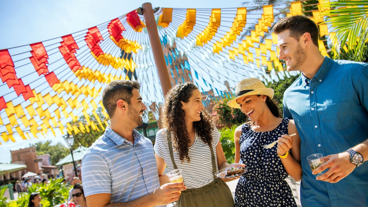 A group of 4 young adults enjoying drinks and a snack at Epcot