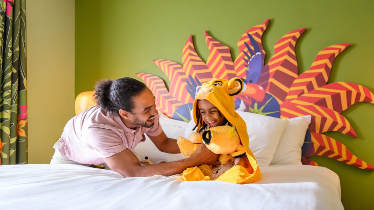 A child laughs with his dad while holding a Simba plush