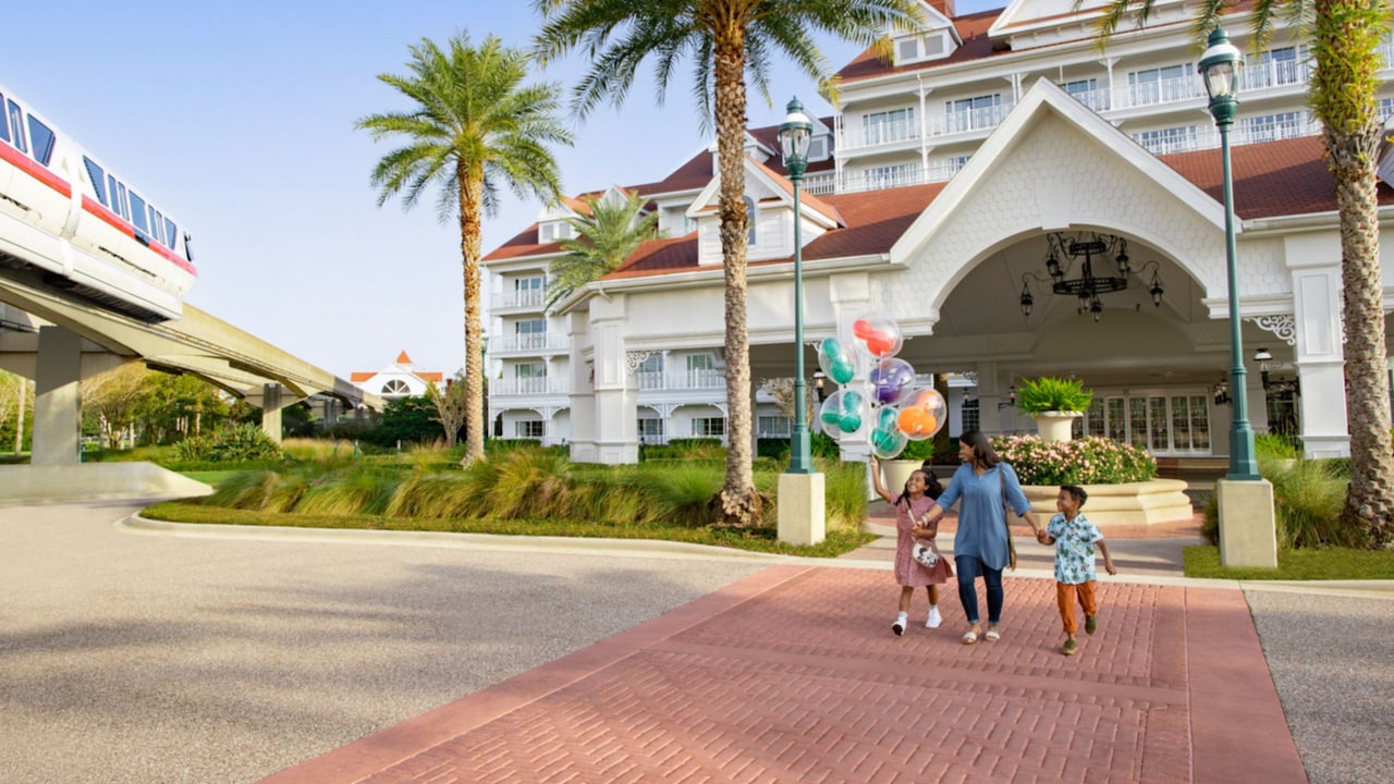 Una madre y sus 2 hijos caminan al aire libre en Disney’s Grand Floridian Resort & Spa