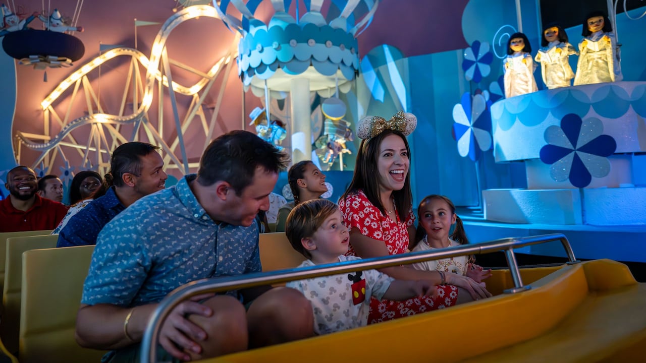 Smiling guests riding the it's a small world attraction  