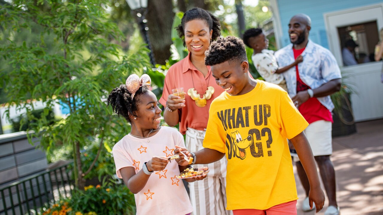 Two parents and their 3 kids walking at epcot with food