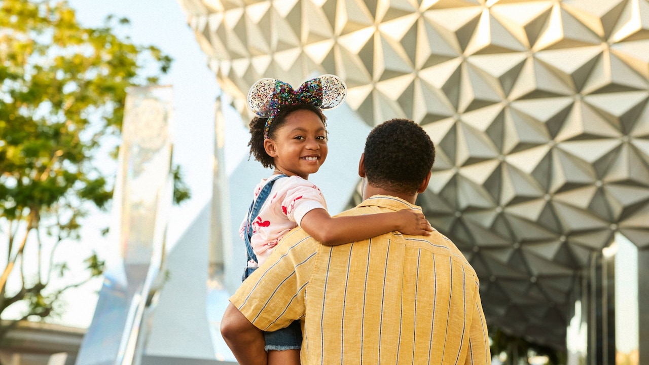  A girl smiling over her father's shoulder near Spaceship Earth at Epcot