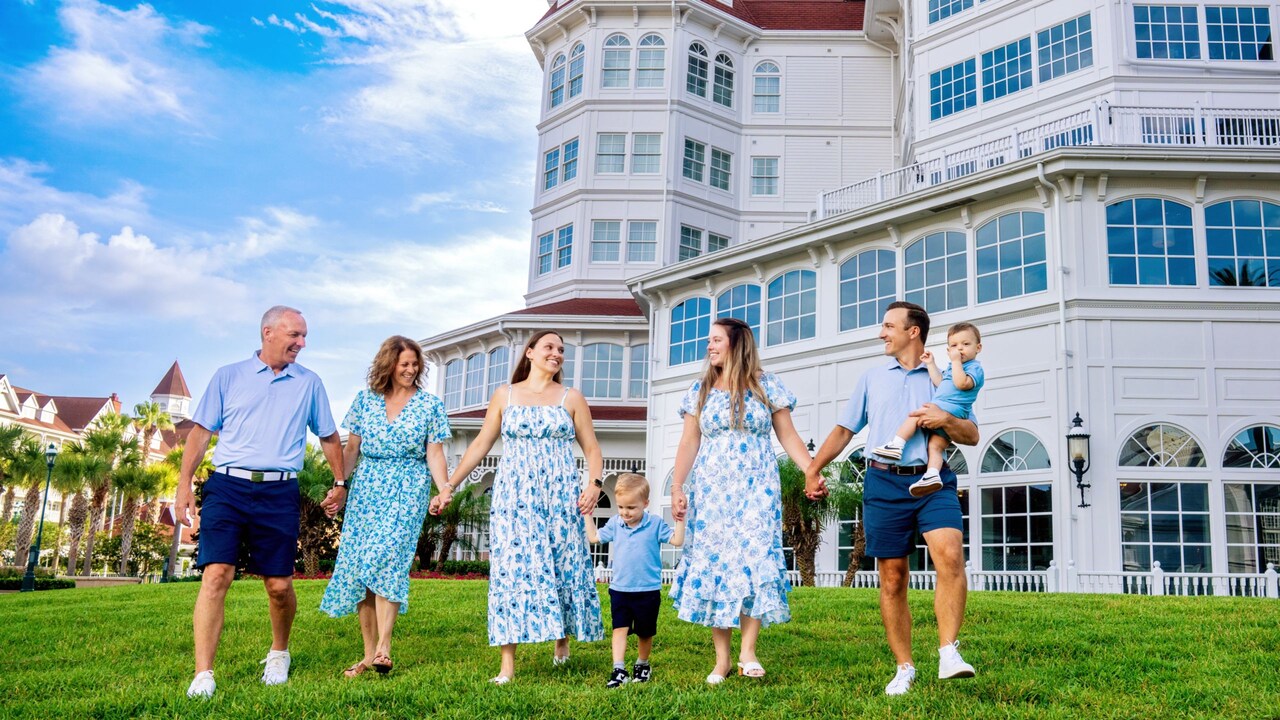 3 generations of a family pose, holding hands outside Disney’s Grand Floridian Resort & Spa