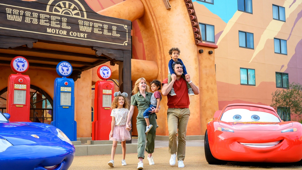 A smiling family walking by the Wheel Well Motel entrance at Disney's Art of Animation Resort