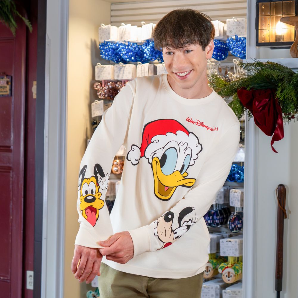 A Guest wearing a Christmas themed Walt Disney World Resort long sleeve shirt featuring Donald Duck, Pluto and Goofy