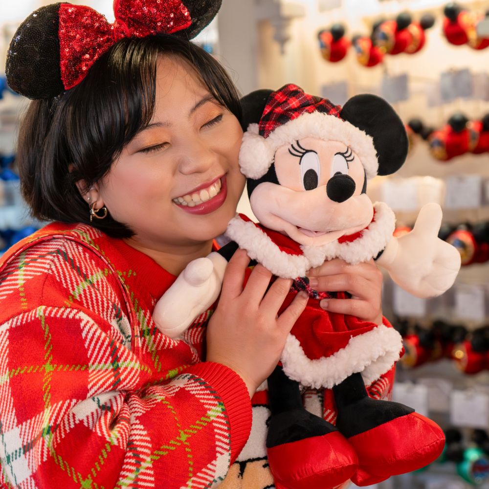 A Guest hugging a Santa Minnie Mouse plush