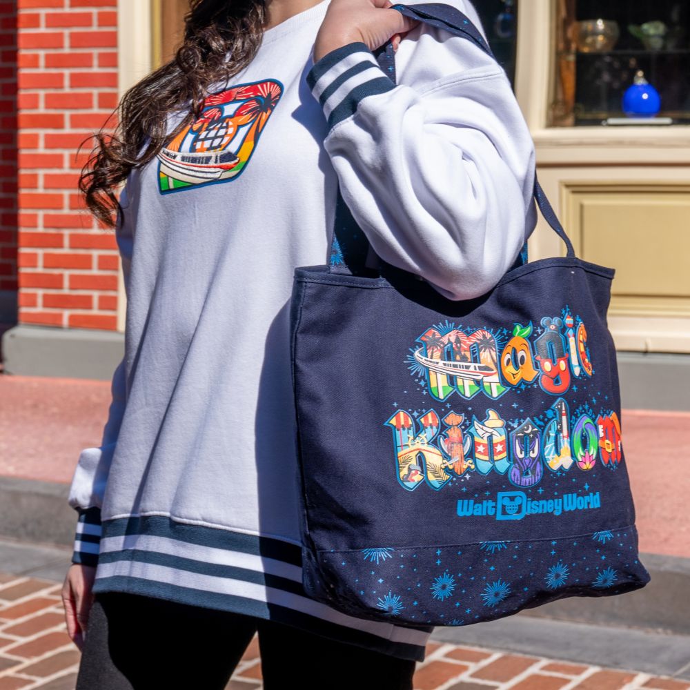 A woman wearing a Walt Disney World Resort sweatshirt and carrying a Magic Kingdom tote bag