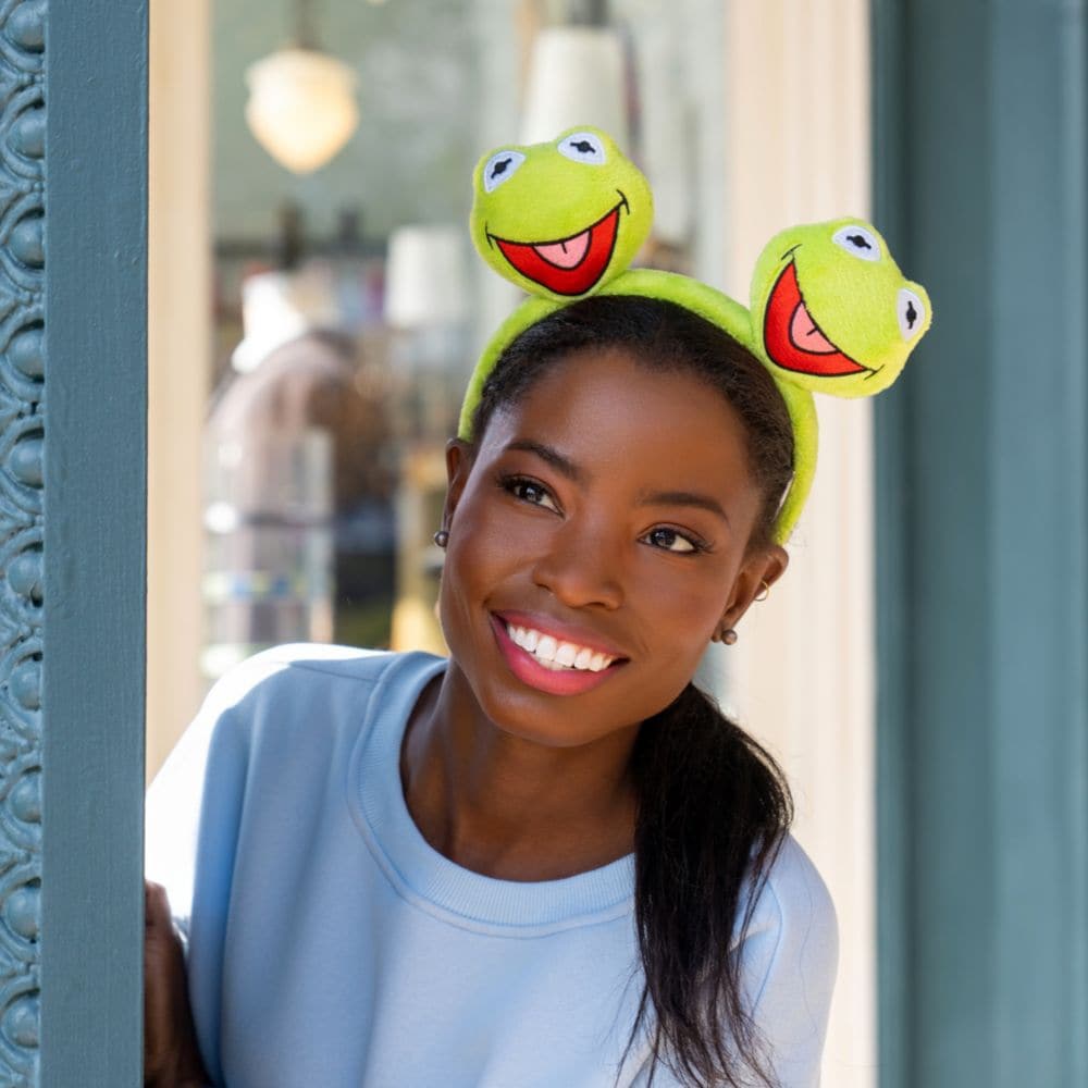 A Guest wearing a Minnie Mouse ear headband featuring Kermit the Frog