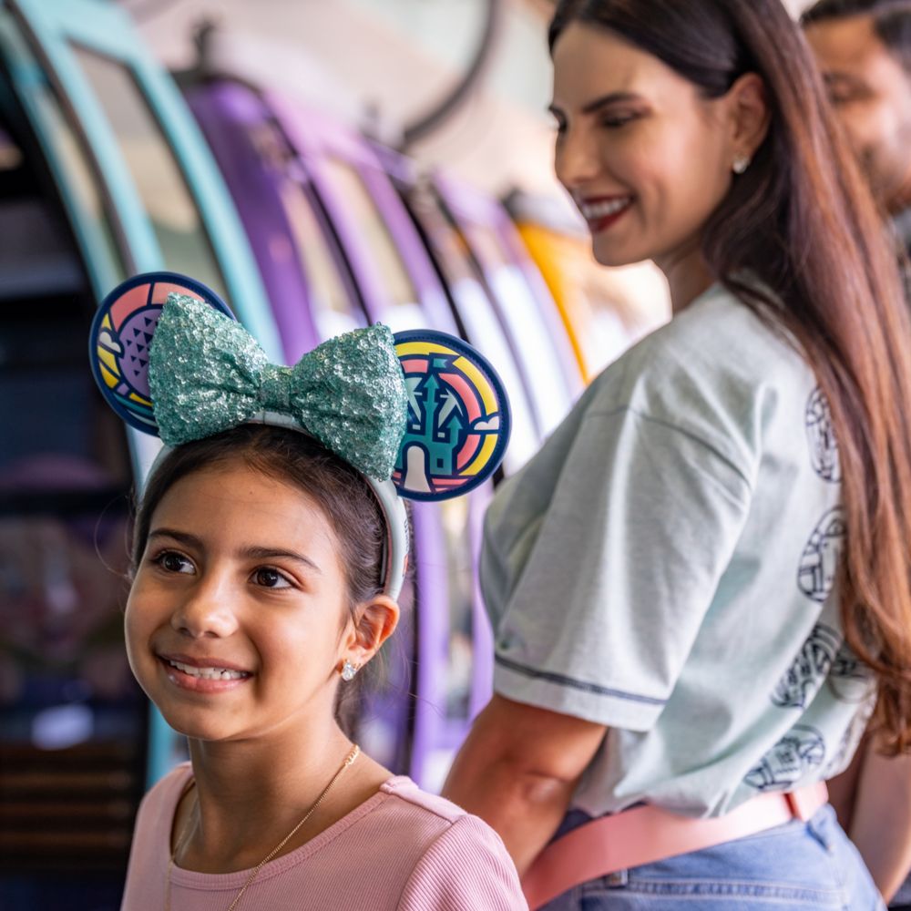 A girl with a Minnie Mouse ear headband smiling next to her mother