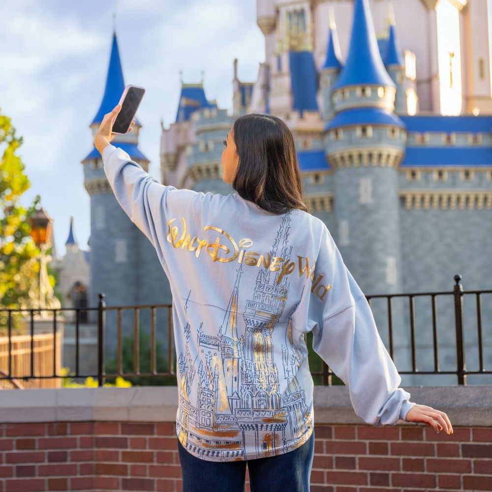 A woman taking a selfie while wearing a sweatshirt featuring Cinderella Castle