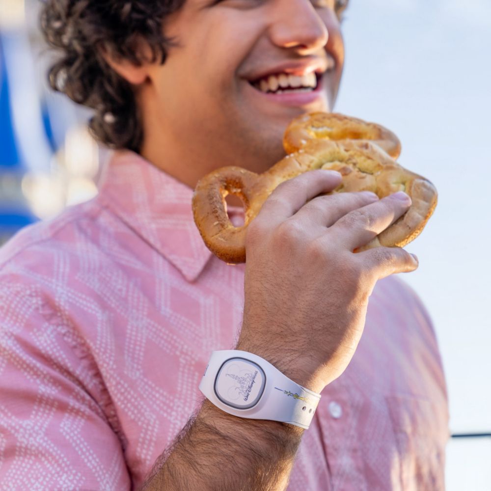 A man eating a Mickey pretzel while wearing a MagicBand