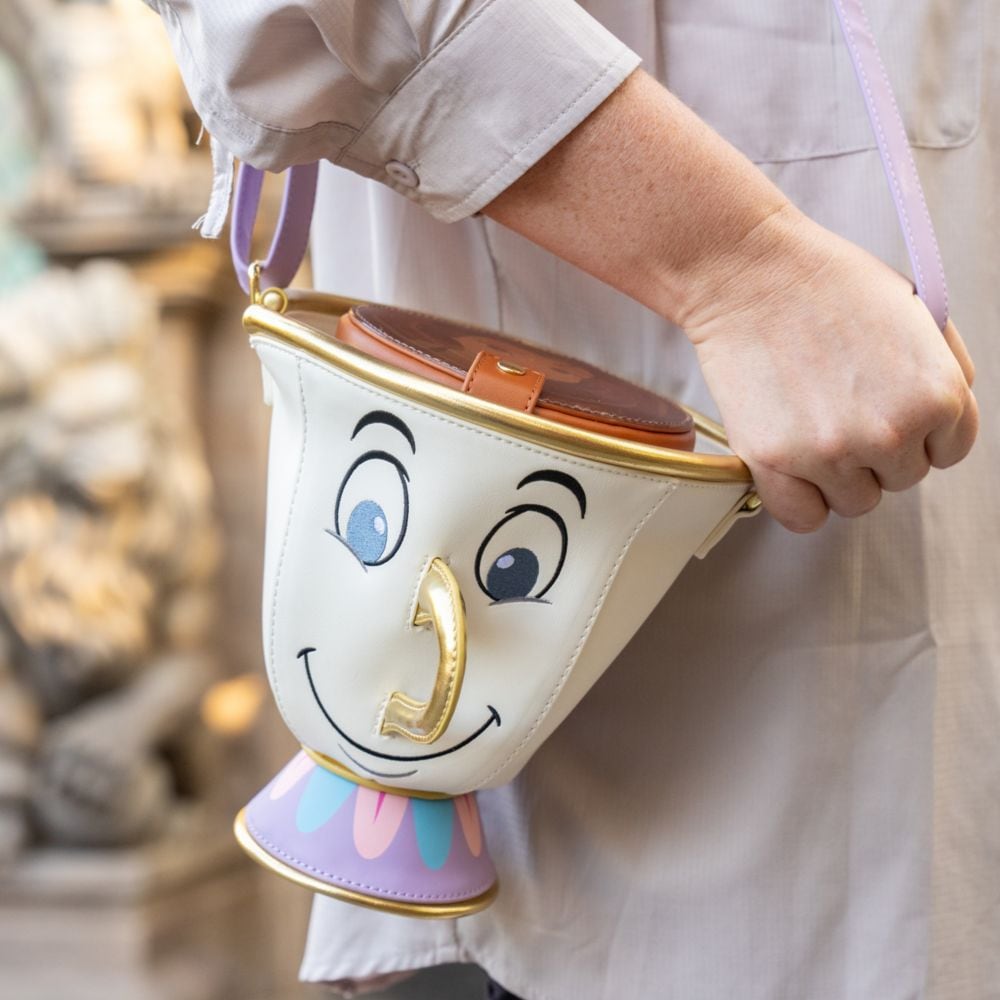 A hand holding a purse shaped like Mrs. Potts