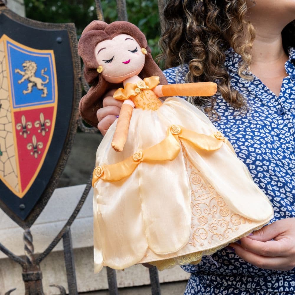 A woman holding a Belle plush doll