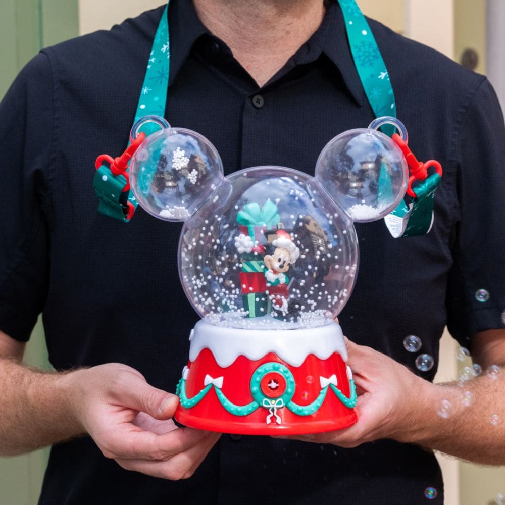 A man holding a Mickey Mouse shaped holiday snow globe popcorn bucket