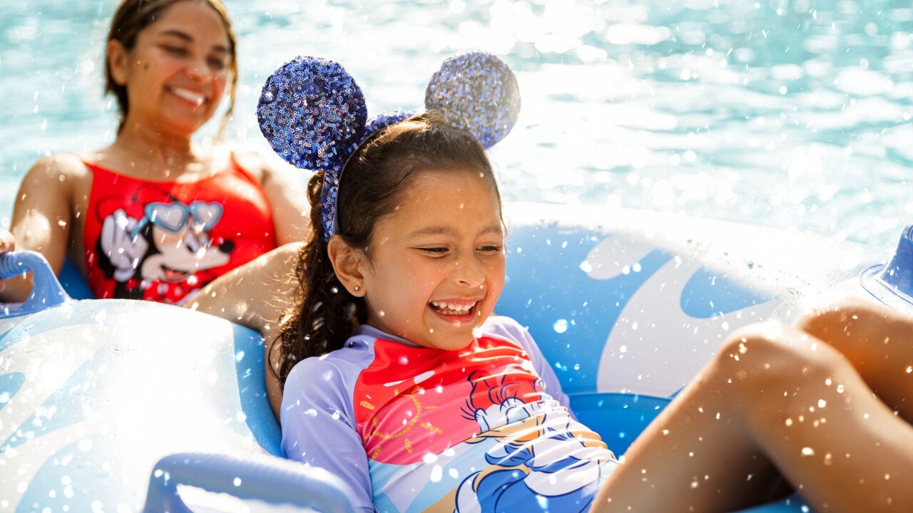A mother and daughter smiling as they float in the water together in a 2 person inner tube