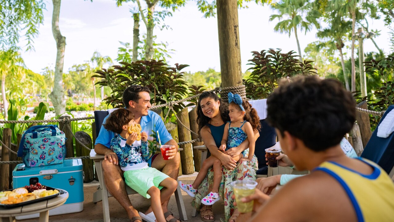 Guests sitting on a patio while enjoying snack and beverages at Disney’s Typhoon Lagoon water park