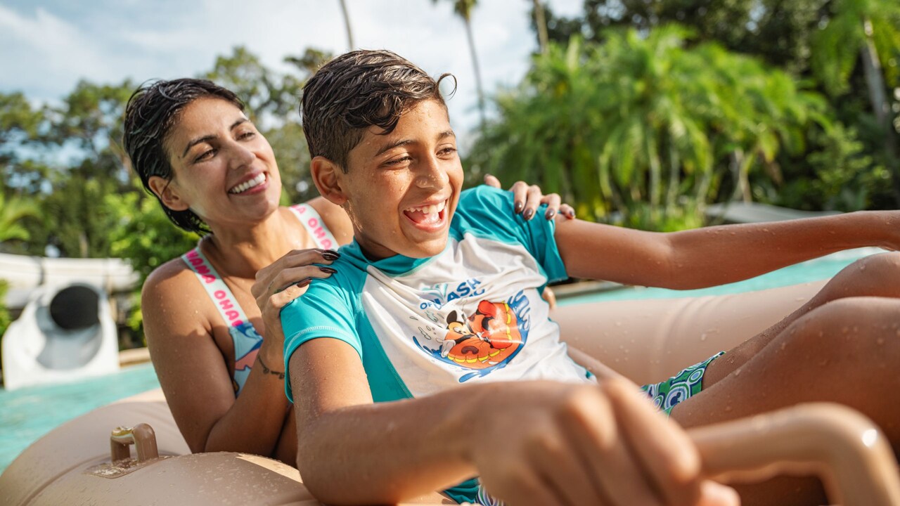 A mother and son riding an inner tube in the pool at the end of the Crush n Gusher waterslide at Disney’s Typhoon Lagoon water park
