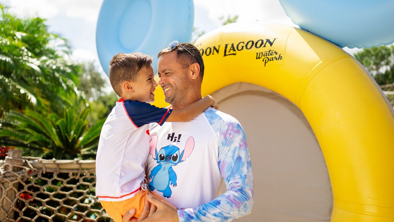 A father holding his son in his arms next to an inner tube at Disney’s Typhoon Lagoon water park