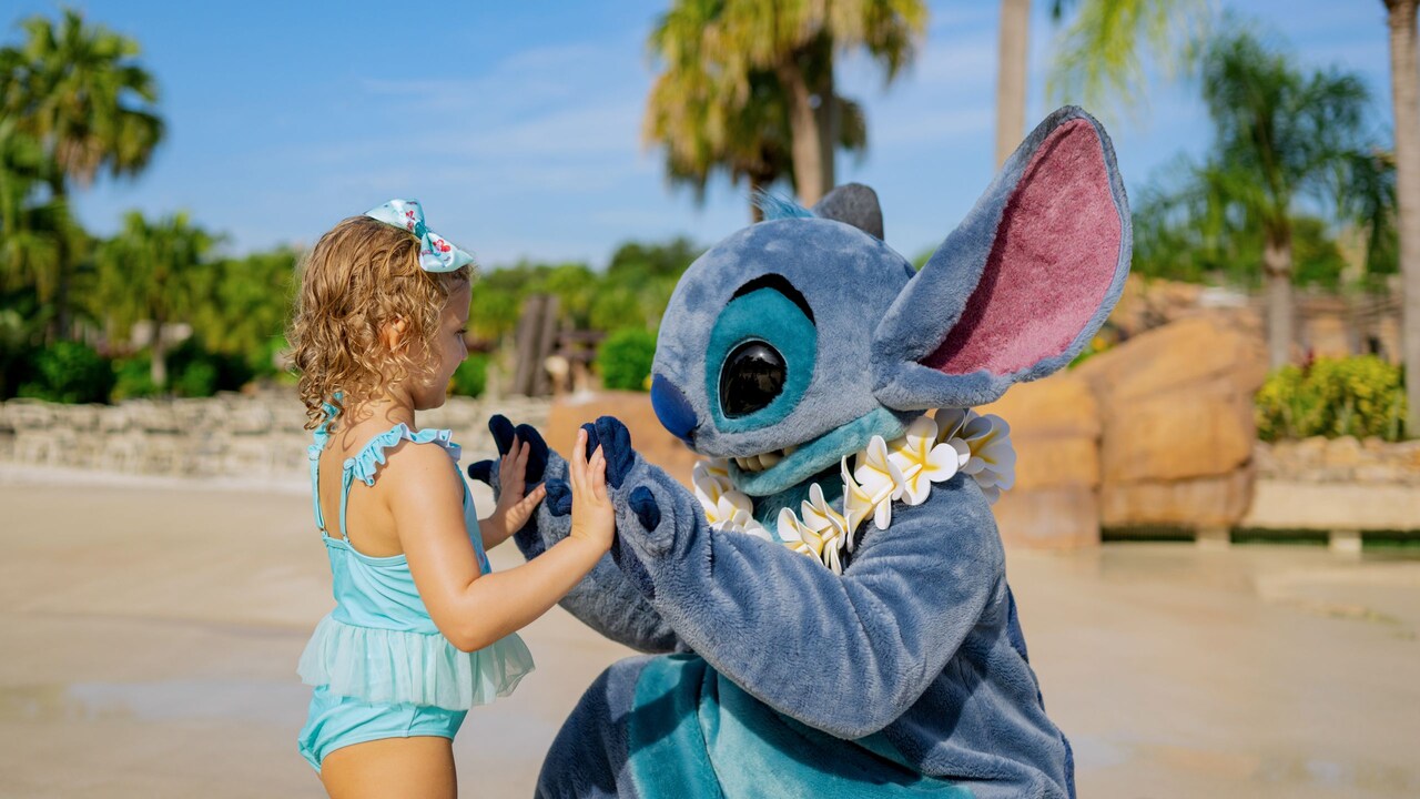 Stitch holding hands with a young girl on the beach