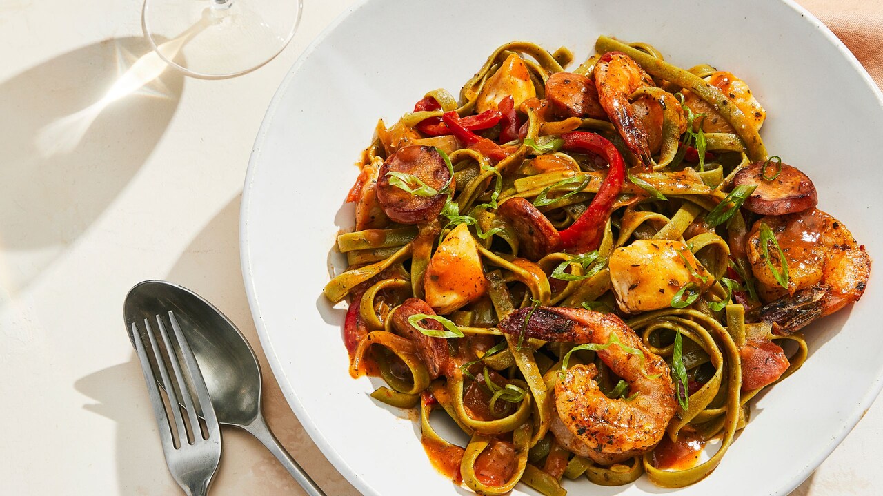 A bowl of spinach fettucini with creole-seasoned shrip, sausage and chicken