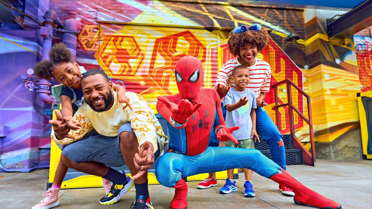 Una familia de cuatro personas posan con Spider Man en Disney California Adventure Park