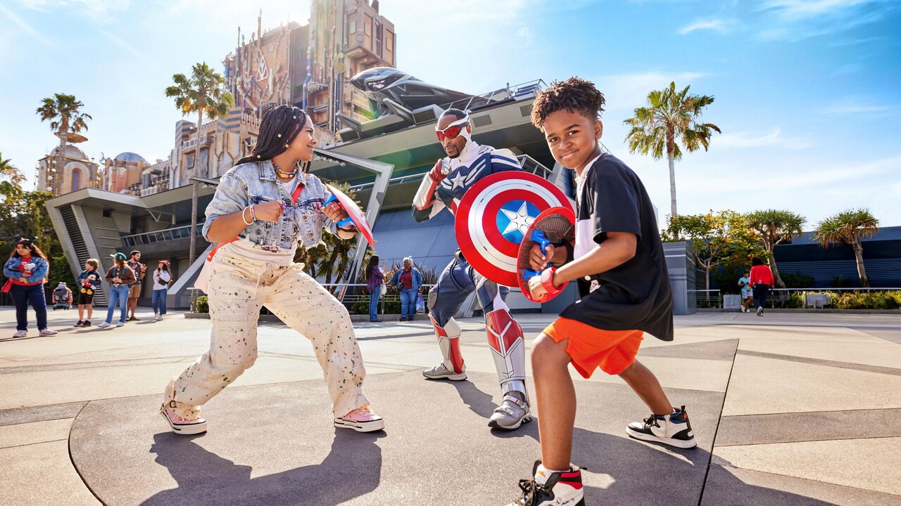 Two children holding shields and posing with Captain America in front of Avengers Headquarters at Disney California Adventure Park