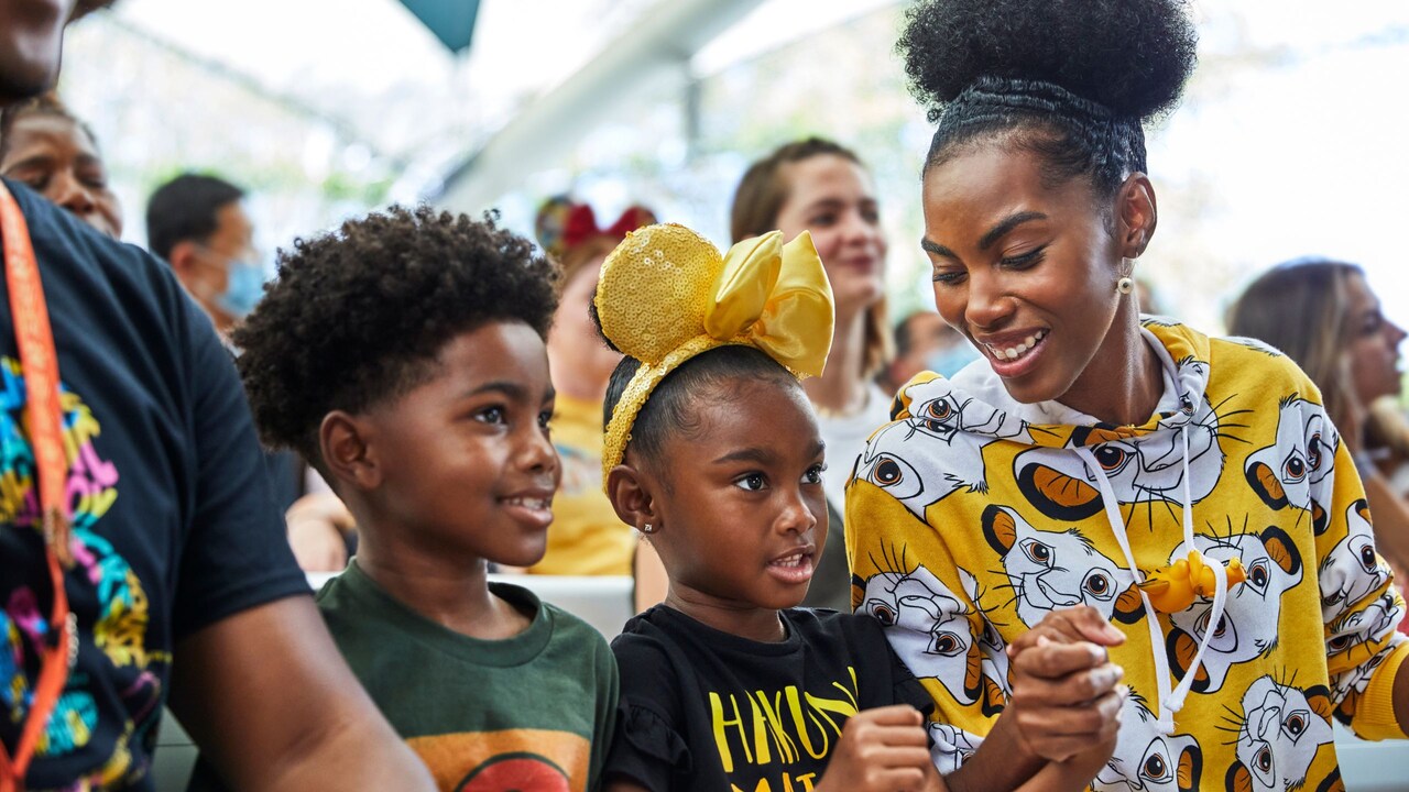 Una familia sonriente sosteniendo sus manos mientras miran una actuación